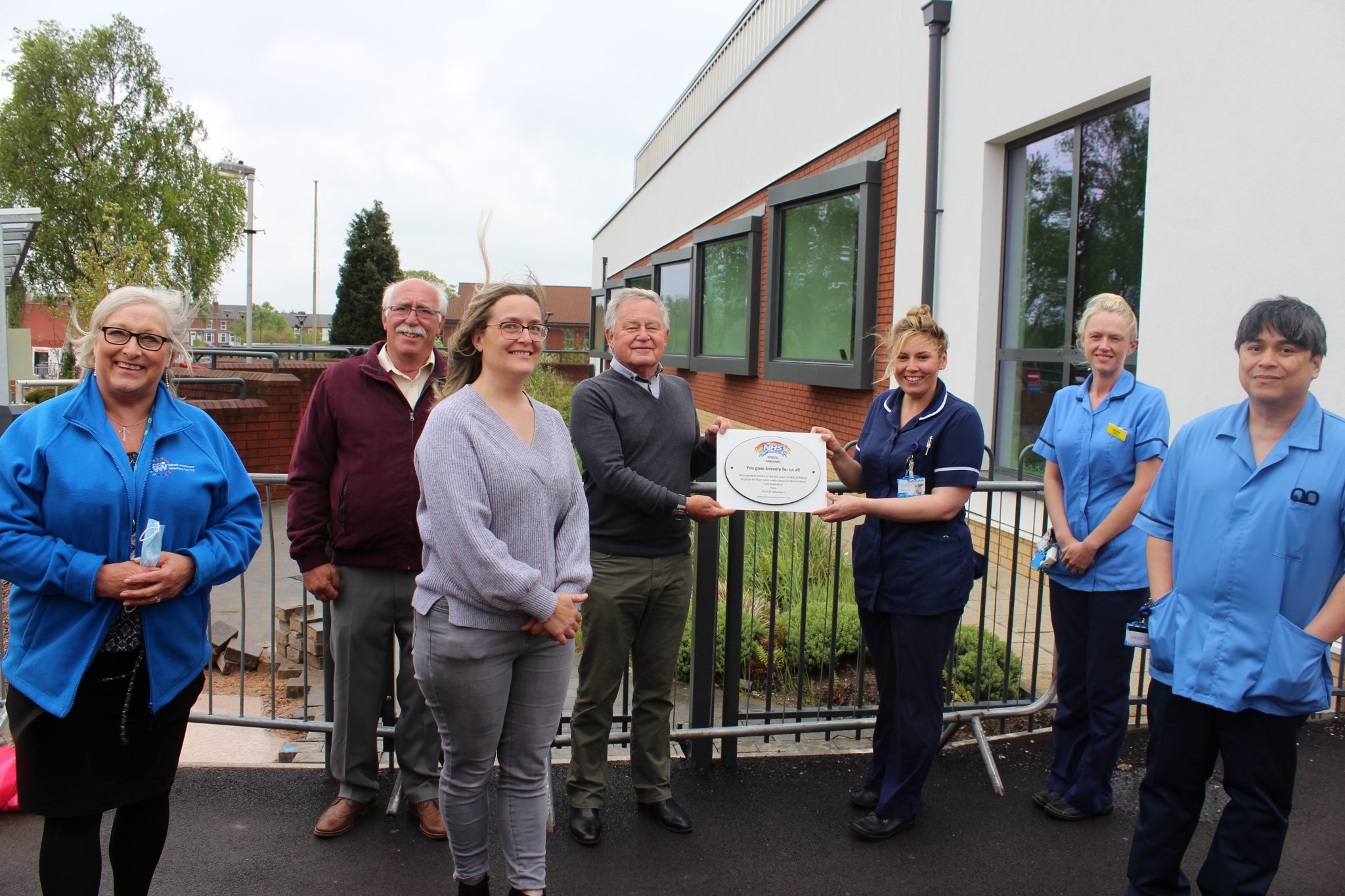 Volunteers hand over the special plaque to critical care staff