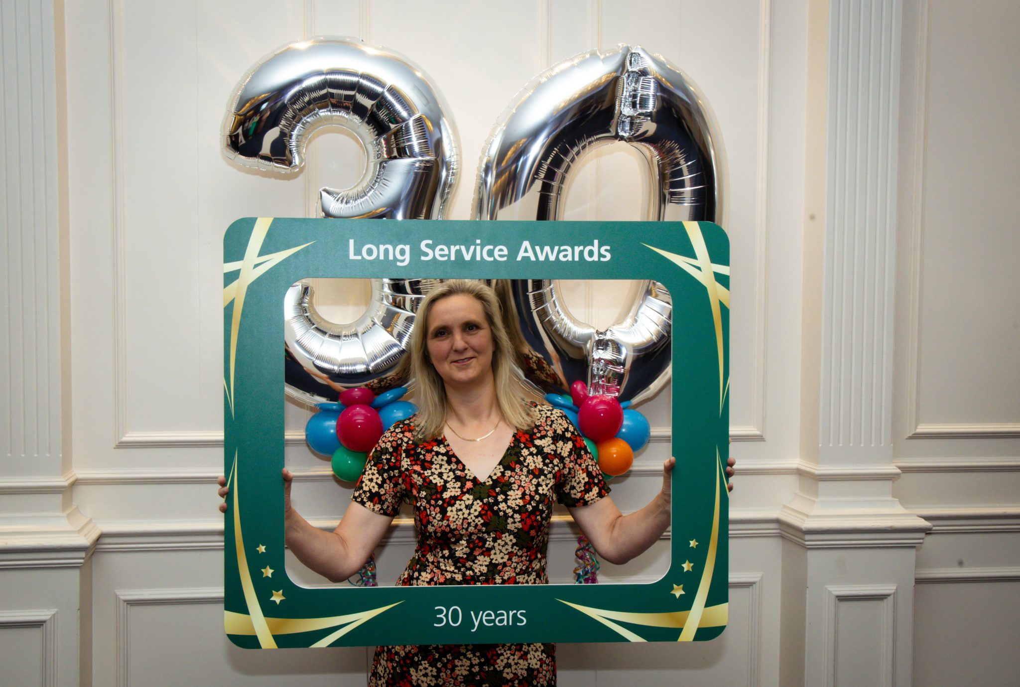 Staff member holding up selfie frame infront of 30 balloon.