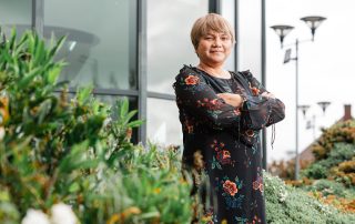 Janet Smith, Head of Sustainability, surrounded by nature outside Walsall Manor Hospital.