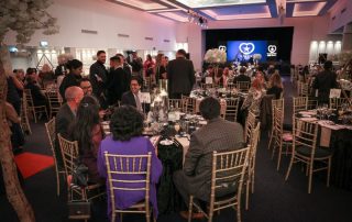 Staff gathered at the 2026 Caring for All Awards - some seated, some socialising as the event is about to begin.